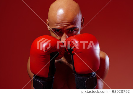 Portrait of sporty man wearing boxing gloves practicing for fight on studio background Portrait of sporty man wearing boxing gloves practicing for fight on studio background 98920792