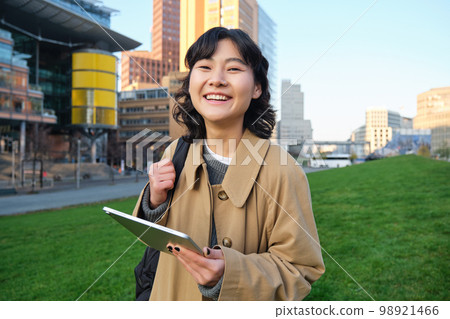 Happy young brunette girl, asian woman walks around city with tablet, goes to university with her digital gadget and backpack 98921466