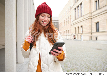 Beautiful smiling girl, tourist with backpack, holding smartphone, using map on mobile phone application, looking for sightseeing in internet app, standing outdoors Beautiful smiling girl, tourist with backpack, holding smartphone, using map on mobile phone application, looking for sightseeing in internet app, standing outdoors 98921897