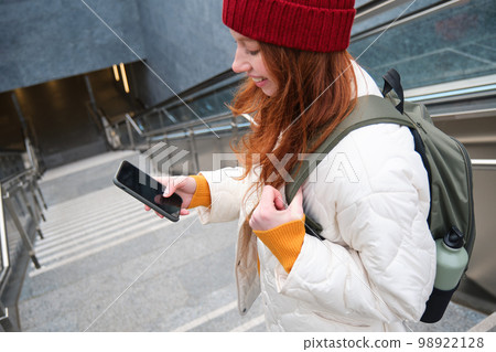 Smiling girl walking on stairs, using mobile phone, texting message on her way, using smartphone app map, follows route to destination place Smiling girl walking on stairs, using mobile phone, texting message on her way, using smartphone app map, follows route to destination place 98922128