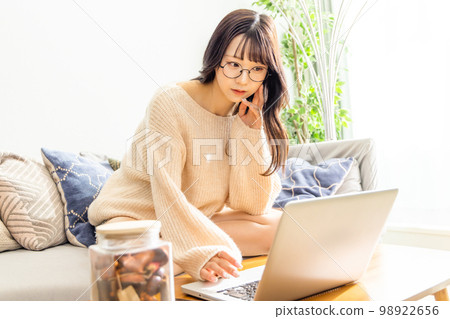 一位女士盤腿坐在沙發上，使用筆記本電腦 98922656