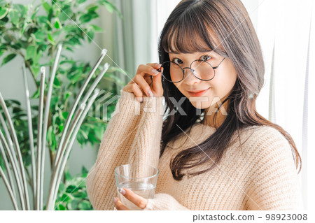 A woman drinking water in a cup 98923008