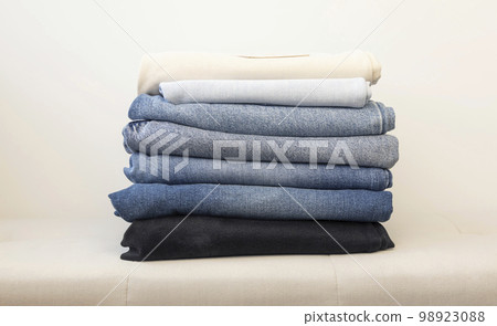 Many jeans stacked on top of each other in different colors. Casual clothing concept. 98923088