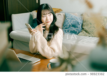 Young woman using smartphone and laptop 98923382