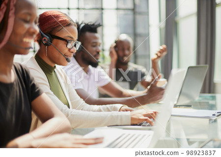 Smiling beautiful African American woman working in call center with diverse team Smiling beautiful African American woman working in call center with diverse team 98923837