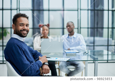 An African-American student sits on a chair in a room. 98923853