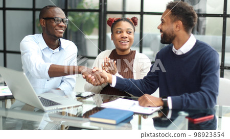 African american business team talking about strategy while looking at laptop, in office 98923854