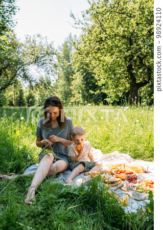 Family mom and son on picnic. Smiling and enjoying summer on blanket in park. Family mom and son on picnic. Smiling and enjoying summer on blanket in park. 98924110
