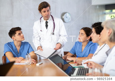 Physician discussing diagnosis of patients with colleagues in office Physician discussing diagnosis of patients with colleagues in office 98925164