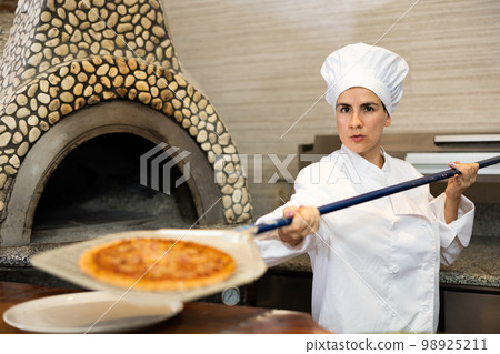 Woman pizza chef at work in restaurant Woman pizza chef at work in restaurant 98925211