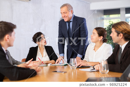 Smiling elderly executive holding work meeting in office Smiling elderly executive holding work meeting in office 98925224