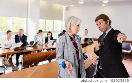 Middle aged white dark-haired male manager dismissing senior white female employee Middle aged white dark-haired male manager dismissing senior white female employee 98925226