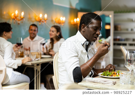 Confident african american man having lunch in a restaurant - eating delicious healthy salad Confident african american man having lunch in a restaurant - eating delicious healthy salad 98925227