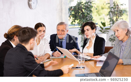 Business partners discussing projects at table in office Business partners discussing projects at table in office 98925230