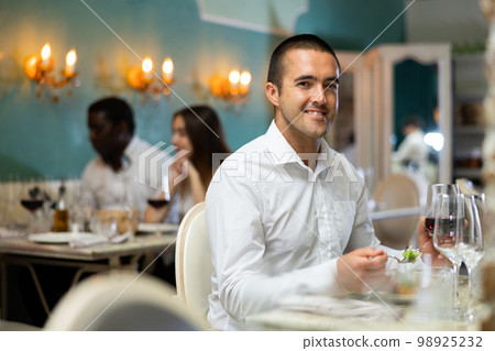 Portrait of man with glass of red wine waiting for woman in restaurant 98925232
