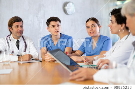 Doctors discussing diagnosis during medical council at table 98925233