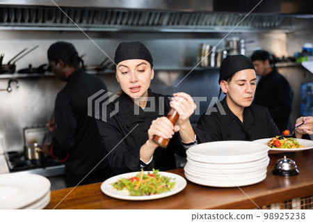 Woman chef seasoning salad before handing it 98925238
