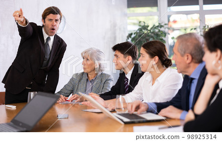 Angry boss scolding subordinates at meeting in office Angry boss scolding subordinates at meeting in office 98925314