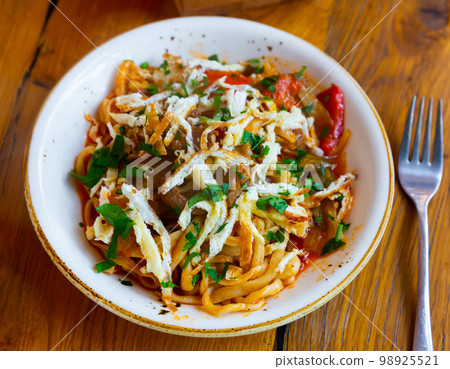 Kaurma lagman or laghman with vegetables, beef meat and oriental spices closeup. Rich asian dish of fried noodles prepared from stringy dough Kaurma lagman or laghman with vegetables, beef meat and oriental spices closeup. Rich asian dish of fried noodles prepared from stringy dough 98925521