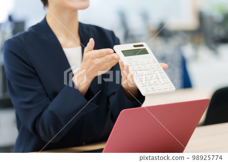 Business woman giving a presentation using a calculator Business woman giving a presentation using a calculator 98925774