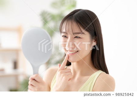 Woman checking her teeth Dental care Woman checking her teeth Dental care 98925842