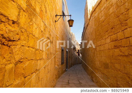 Mdina, Malta - 12 15 22: sandstone walls of narrow Mdina street Mdina, Malta - 12 15 22: sandstone walls of narrow Mdina street 98925949