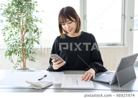 Asian woman filing tax return on smartphone 98925974