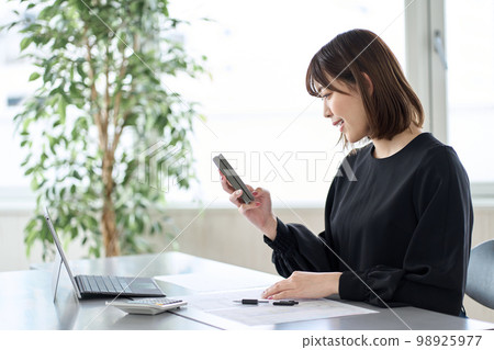 Asian woman filing tax return on smartphone 98925977
