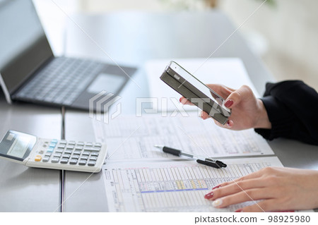 Asian woman filing tax return on smartphone 98925980