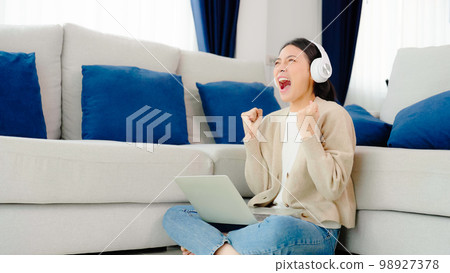 Funny euphoric young asian woman celebrating winning Funny euphoric young asian woman celebrating winning 98927378