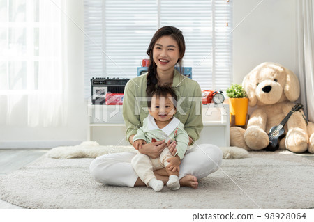 Happy mom and baby boy sitting on carpet smile and cheerful spending time for good moment together at home. Asian baby toddler relaxing with mother. Mother's day concept. 98928064