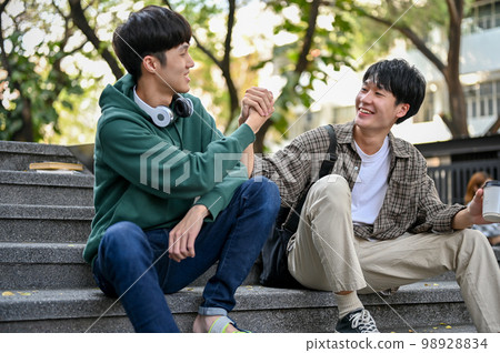 Happy Asian male college student having friendly handshake with his friend. greeting, say hi Happy Asian male college student having friendly handshake with his friend. greeting, say hi 98928834
