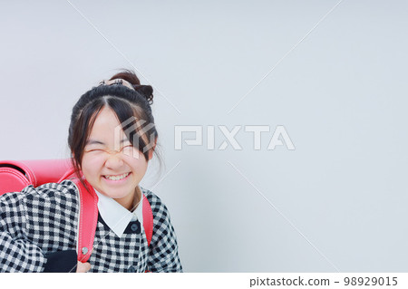 A girl with a big smile carrying a school bag 98929015