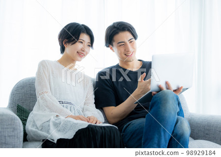 A couple looking at a computer in the living room A couple looking at a computer in the living room 98929184