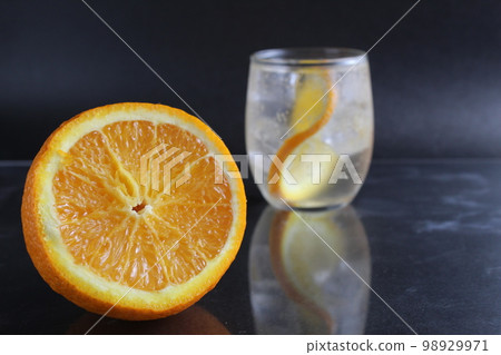 lemonade with orange and ice in a glass on a black background next to lies ice and orange. Summer drink on a black background lemonade with orange and ice in a glass on a black background next to lies ice and orange. Summer drink on a black background 98929971