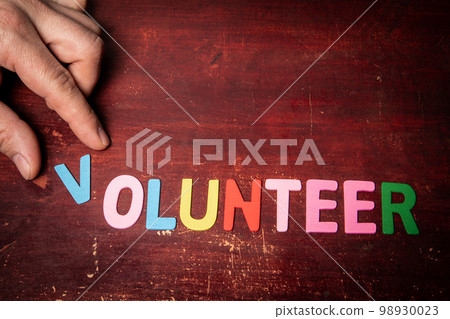 VOLUNTEER. Text from colorful letters on a wooden background VOLUNTEER. Text from colorful letters on a wooden background 98930023
