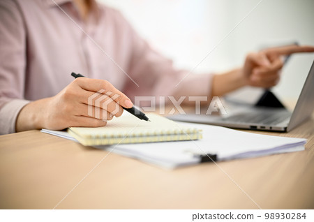 Professional Asian businesswoman working at her desk, taking notes on her spiral notepad. Professional Asian businesswoman working at her desk, taking notes on her spiral notepad. 98930284
