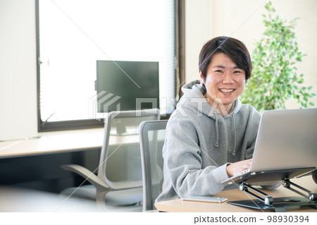A young man wearing a hoodie to work 98930394
