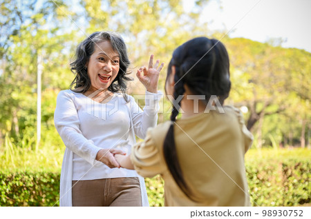 Overjoyed Asian grandmother and granddaughter enjoy playing game together in the park 98930752
