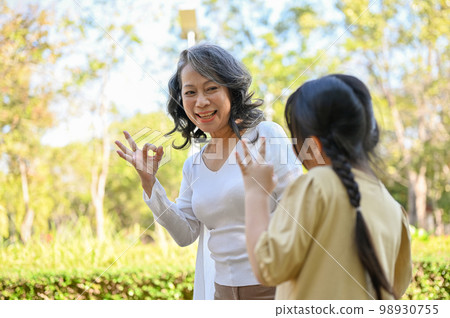 Cheerful Asian grandmother and granddaughter showing okay hand sign, playing game in the park 98930755