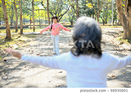 An adorable Asian granddaughter running to her grandmother, playing fun game in the park 98930801