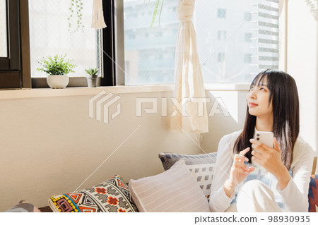 一位女士在低沙發上使用智能手機 98930935