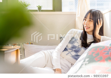 在低沙發上放鬆的年輕女人 98931097