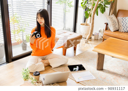 Young woman sitting on the floor and working 98931117