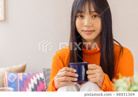 Young woman standing on her knees and drinking coffee/tea 98931304