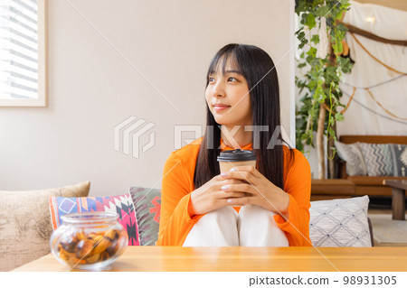Young woman standing on her knees and drinking coffee/tea 98931305