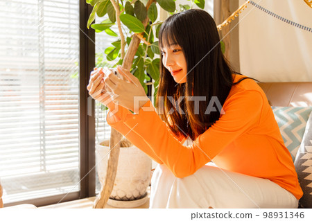 Woman enjoying videos on her smartphone 98931346