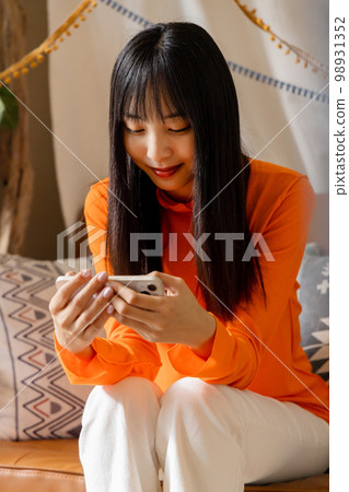 Woman enjoying videos on her smartphone 98931352