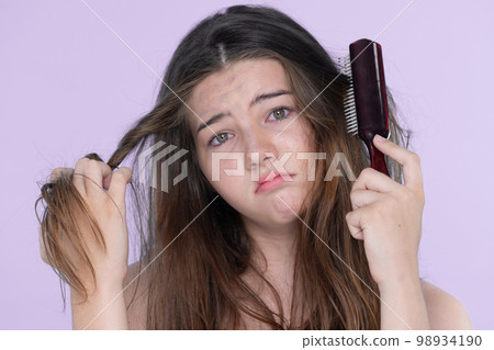 Beautiful girl worry about her damaged hair with isolated background. 98934190
