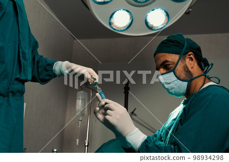 Surgeon fill syringe from vial for surgical procedure at sterile operation room. Surgeon fill syringe from vial for surgical procedure at sterile operation room. 98934298